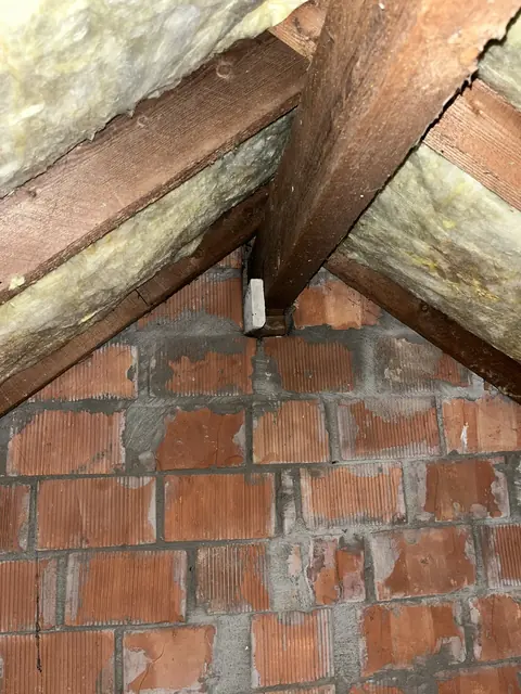 Houten dakspanten tegen een bakstenen muur